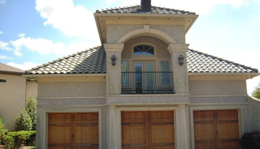 Front exterior view showing the three-bay garage and an upper balcony framed with a decorative arch.