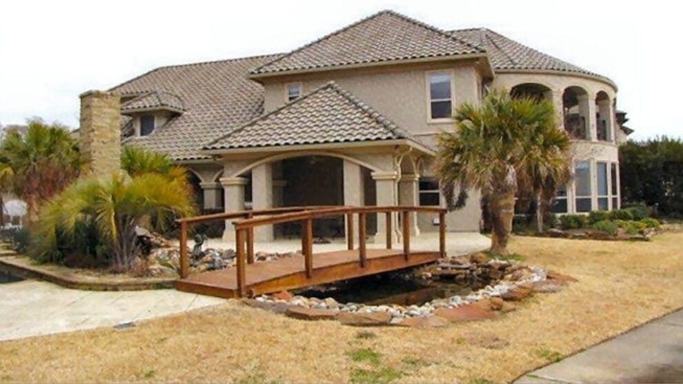 A farther view shows the man-made pond adorned with a wooden bridge.