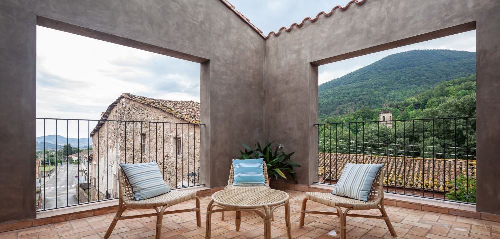 A balcony with wooden chairs and table.