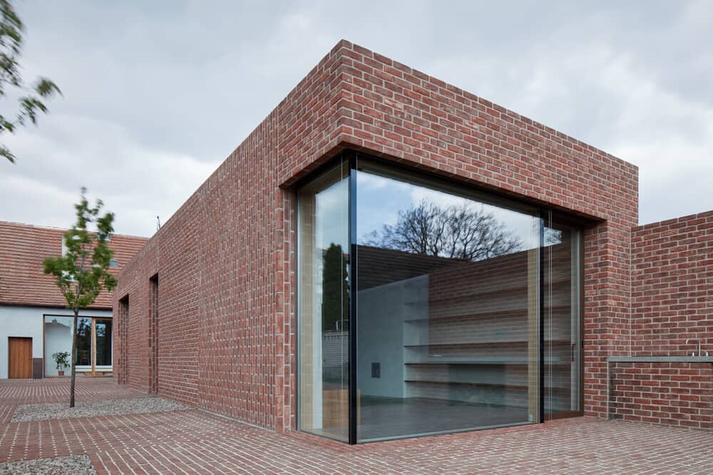 This is a side of the house with a corner glass wall that contrasts the red brick exteriors.