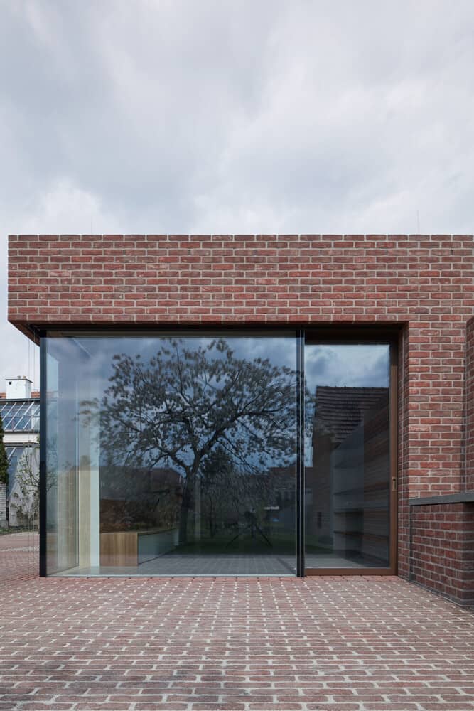 This is a close look at the large glass wall of the house with a view of the interiors and a small entryway on the side.