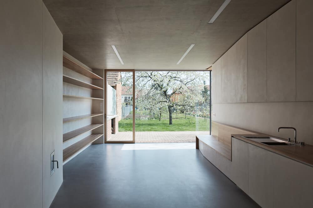 Inside the large glass wall is the kitchen with large built-in wooden structures.