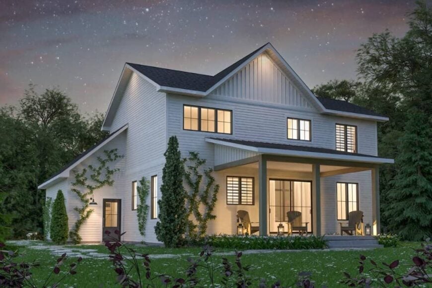 Rear exterior view with a covered porch illuminated with outdoor lamps along with warm lights from the interior.