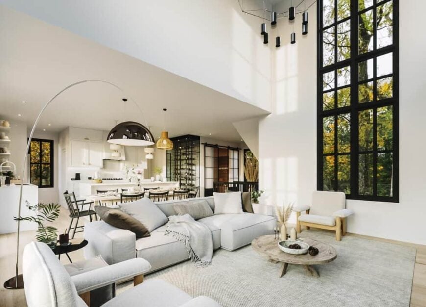 The cushioned armchair and gray sofa are paired with a round coffee table sitting over a large area rug.