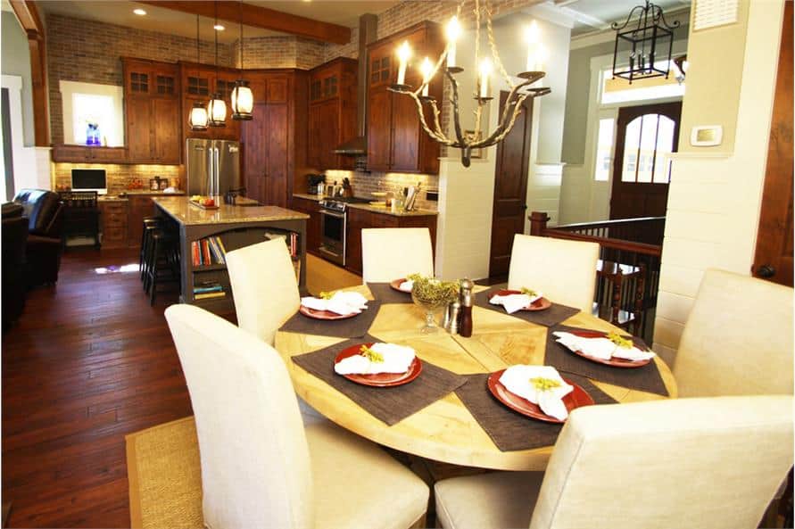 Dining area with beige upholstered chairs and a round dining table well-lit by a warm chandelier.
