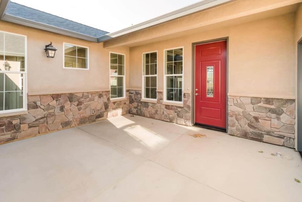 A red entry door stands out against the beige exterior of the house.