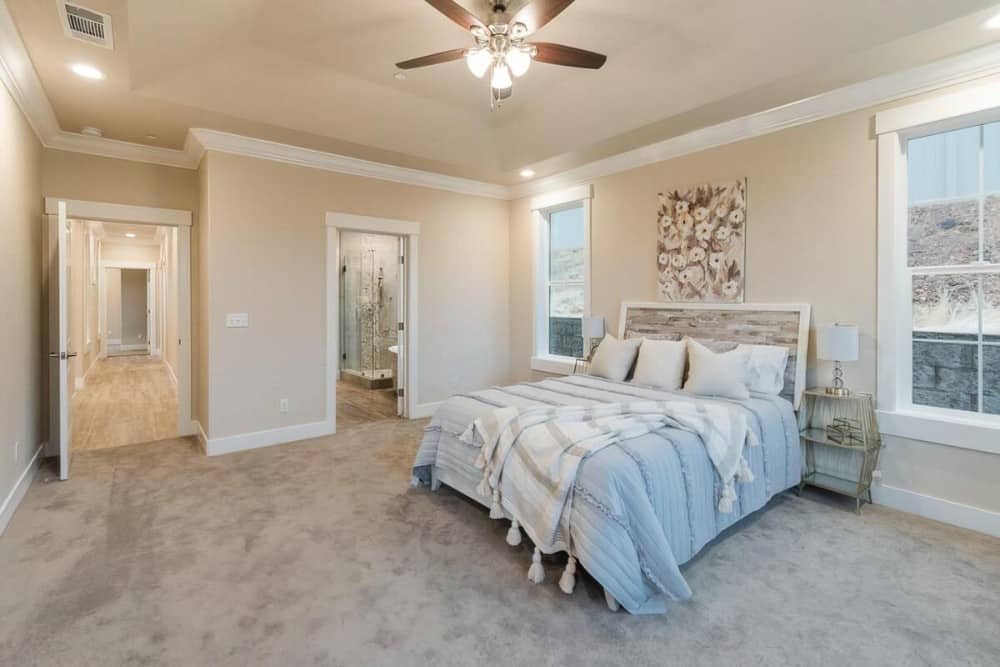 Primary bedroom with carpet flooring and a cozy wooden bed adorned with floral artwork.