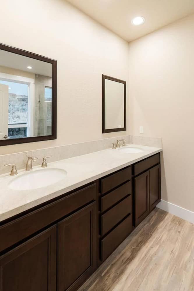 The dark wood vanity is topped with double sinks and a couple of framed mirrors.