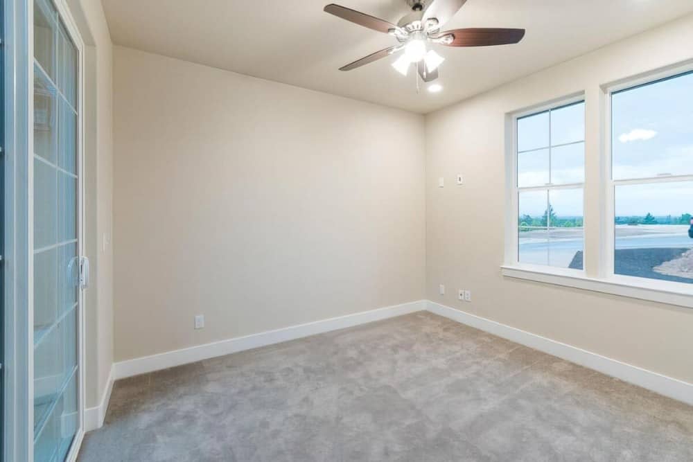 Bedroom with beige walls, carpet flooring, and a regular ceiling mounted with a traditional fan.