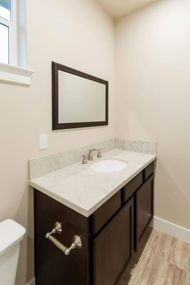 The single sink vanity is paired with a wooden framed mirror.