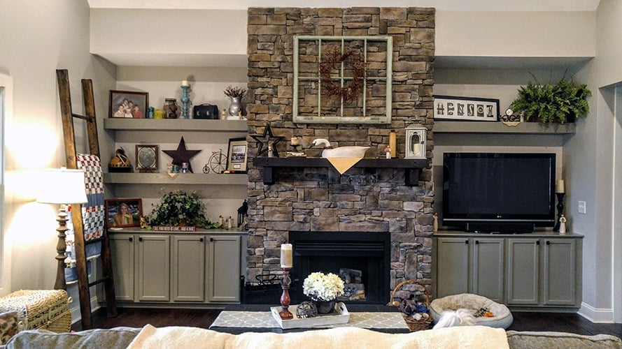 The great room features a stone fireplace flanked by built-in shelves and cabinets.