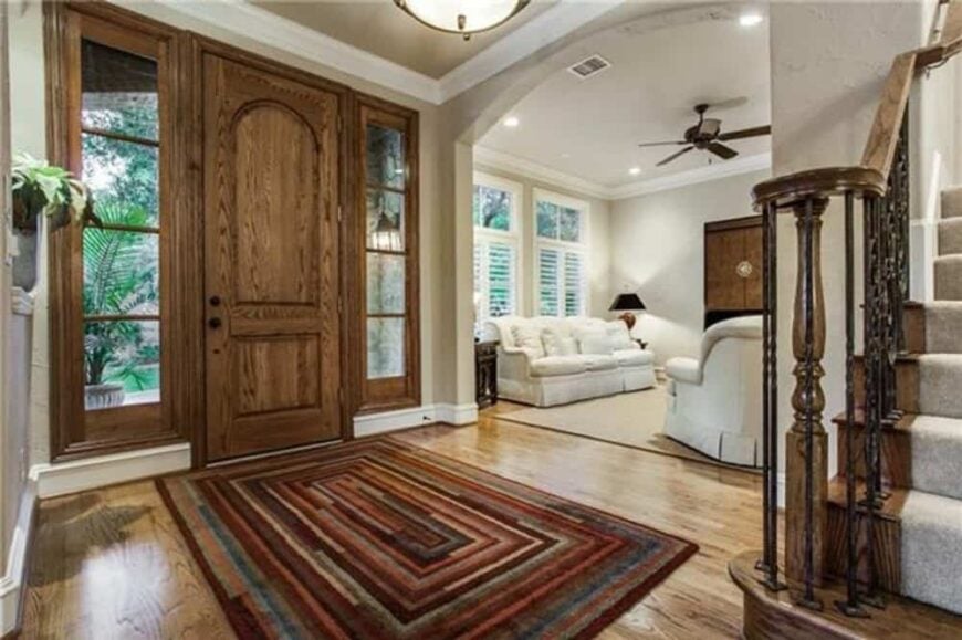 Foyer with a large area rug and a wooden front door flanked by sidelights.