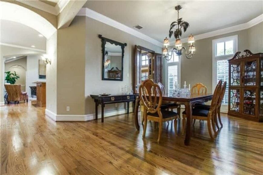 Dining room with a display cabinet, a dark wood buffet table, and wooden dining set illuminated with a warm chandelier.