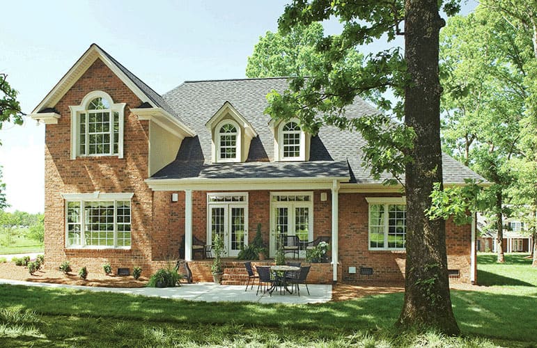 Rear exterior view with concrete patio and a covered porch topped with gable dormers.