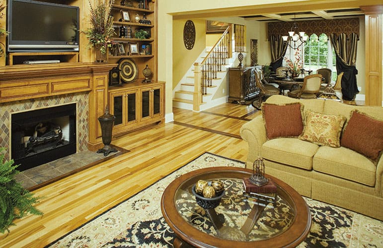 The great room has a beige sofa, a round coffee table, and a TV fixed above the fireplace.