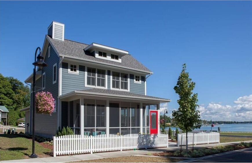 Front exterior view showcasing its blue siding, shed dormer, and screened porch with a vibrant red door.