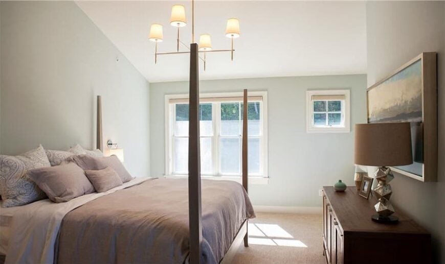 Primary bedroom with a vaulted ceiling, a wooden console table, and a four-poster bed illuminated with a warm chandelier.Primary bedroom with a vaulted ceiling, a wooden console table, and a four-poster bed illuminated with a warm chandelier.