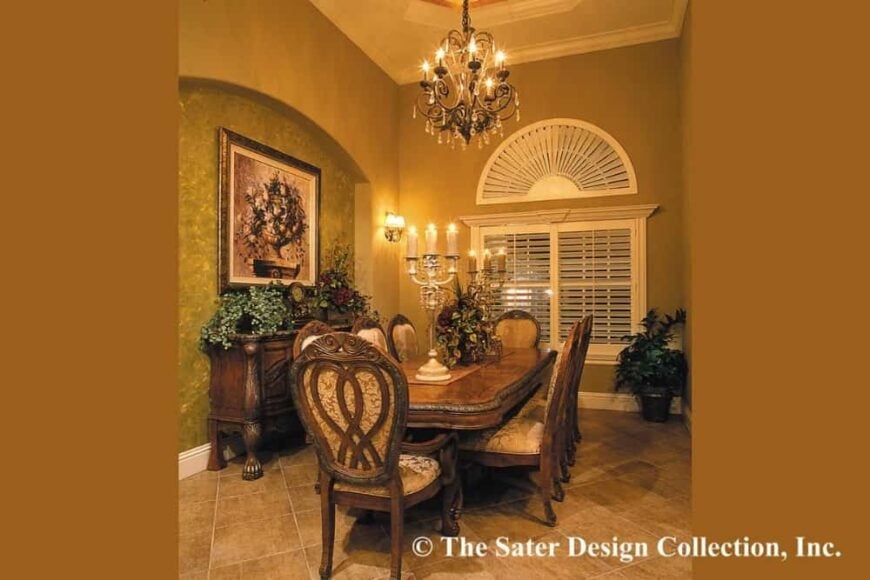 Formal dining room with a wooden buffet table and a matching dining set well-lit by candles and a crystal chandelier.