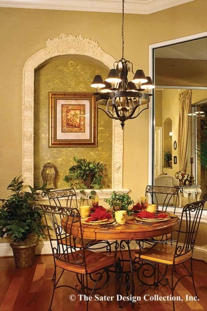Breakfast nook with a round dining set and a wall niche decorated with a potted plant and framed artwork.