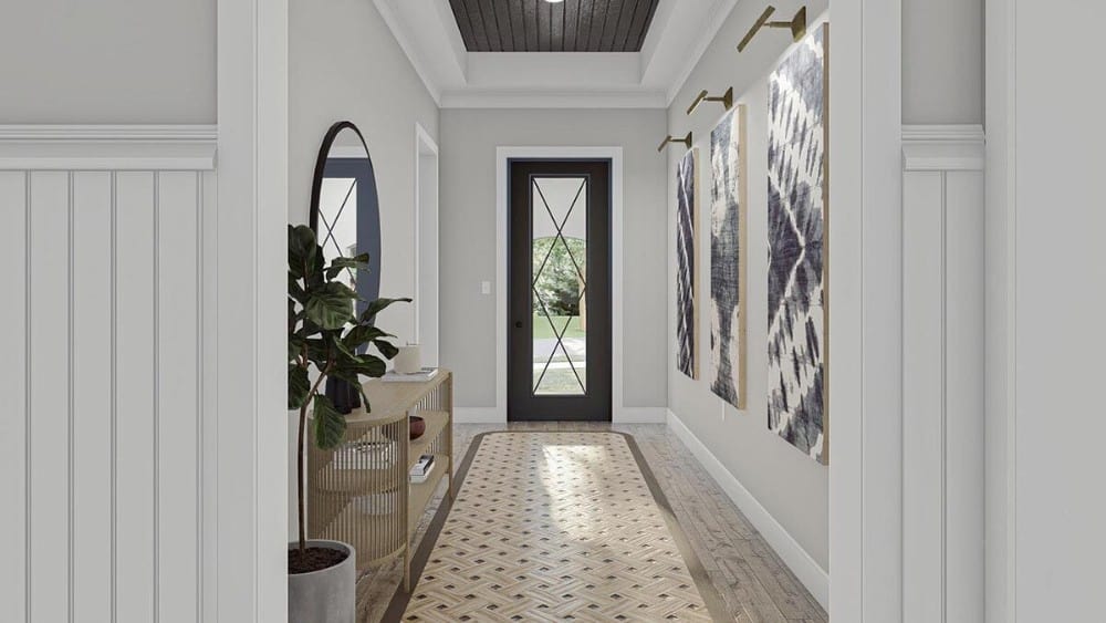 Foyer with a glazed front door, a wicker console table, and light gray walls adorned with a round mirror and large artworks.