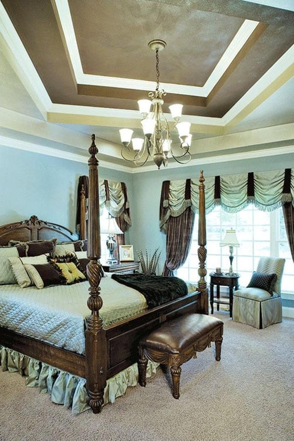 Primary bedroom with a step ceiling, carpet flooring, a four-poster bed, and a sitting area by the large window.