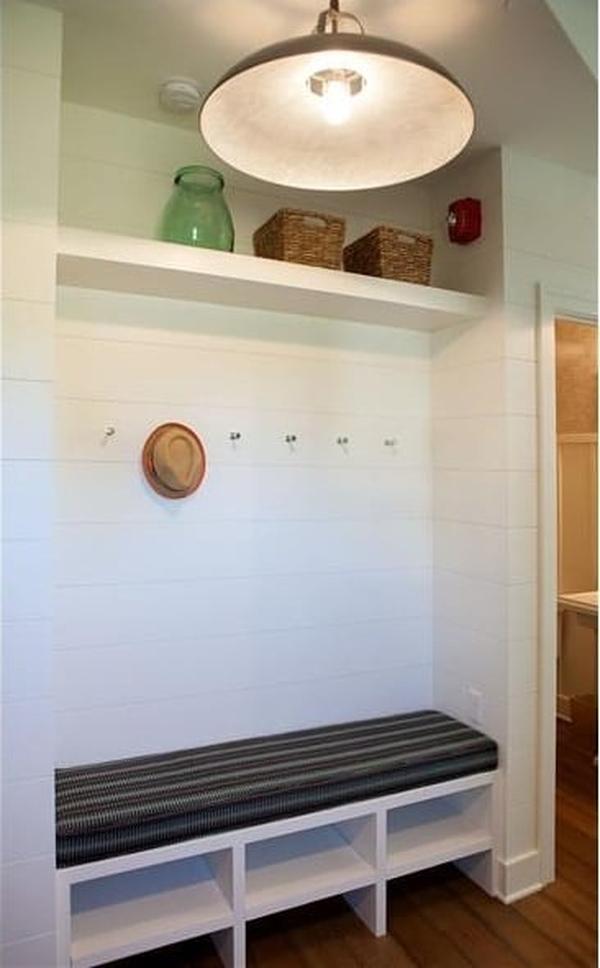 Mudroom with built-in shelves and a cushioned bench brightened by an oversized dome pendant.