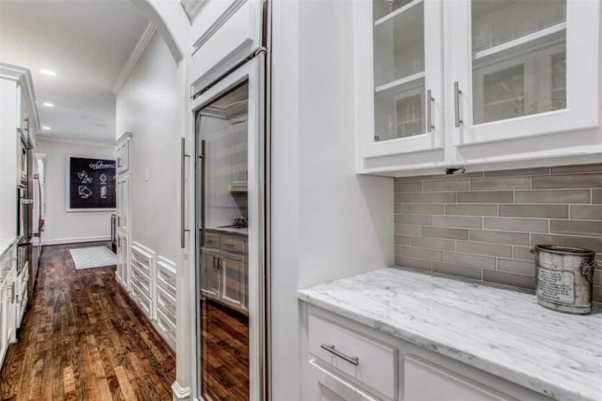 Butler's pantry with glass-front and white cabinets, a marble top counter, and a wine fridge.