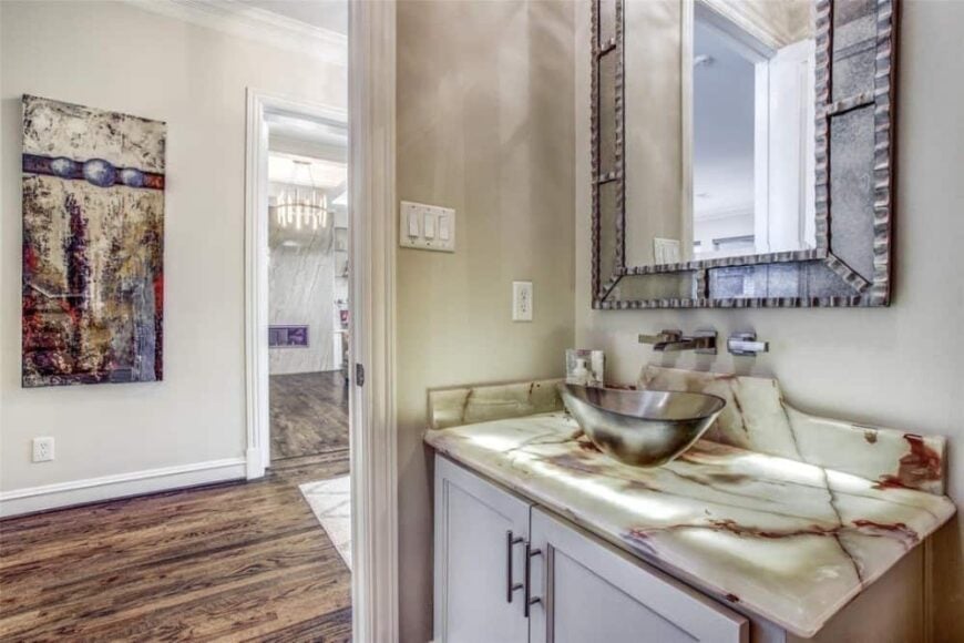 The powder room features a vessel sink vanity topped with a decorative mirror.