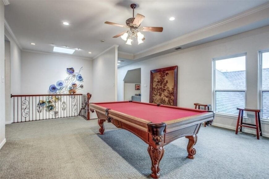 The game room has a billiards table and wooden stools over carpet flooring.