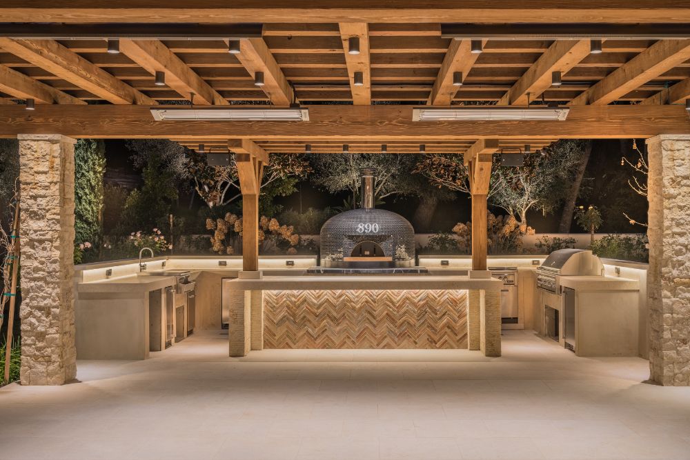 Outdoor kitchen with marble counters under beamed ceiling.