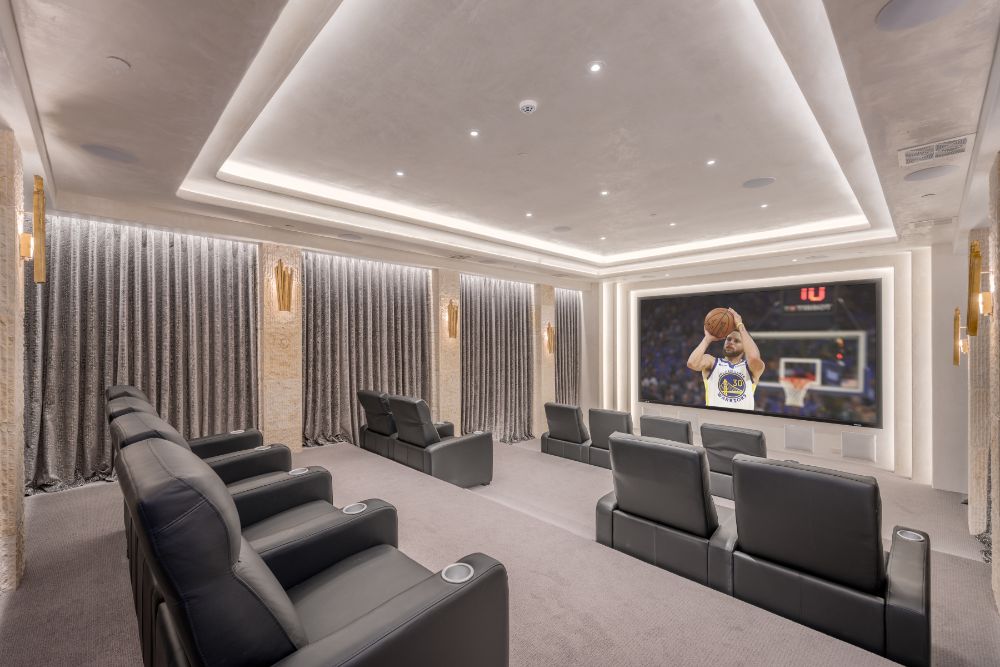 An atmos Dolby screening room with wide screen, leather audience seats and cove type ceiling.