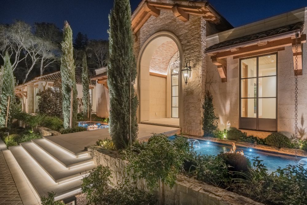Close view of the main home entrance area with landscaped gardens and fountains.