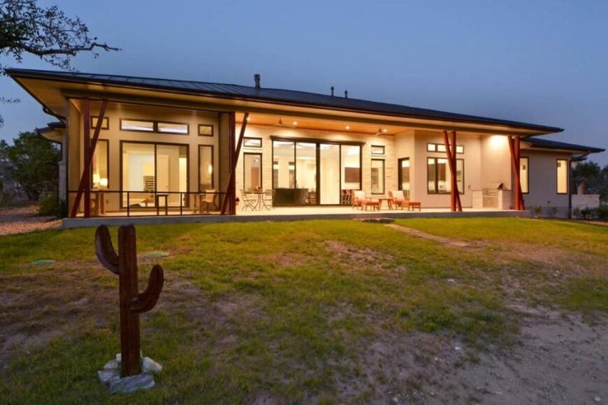Rear exterior view with an expansive covered porch illuminated by warm outdoor lamps.