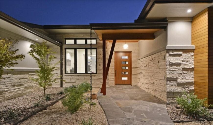 Covered entry with flagstone flooring and a wooden front door fitted with glass panels.