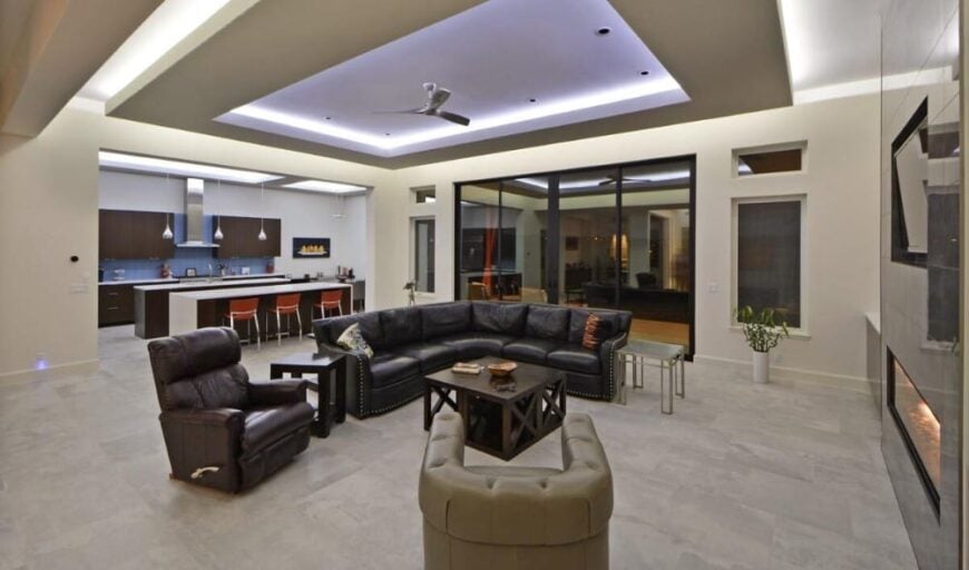 The great room includes leather seats and dark wood tables over limestone flooring.