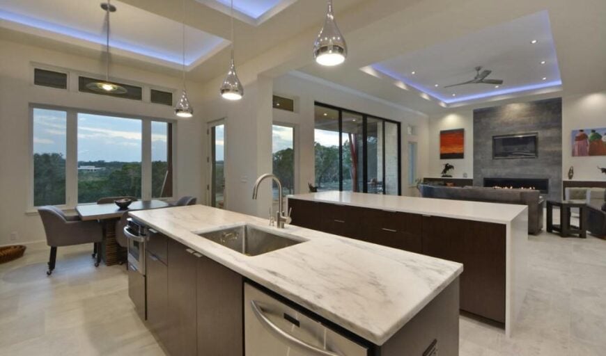 A closer look at the kitchen island fitted with a sink, an oven, and a dishwasher.