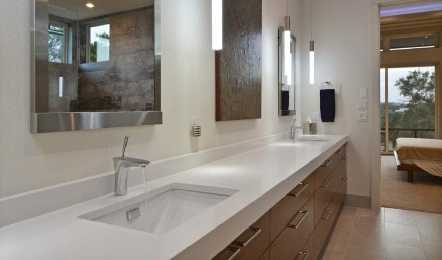 A closer look at the dual sink vanity topped with chrome framed mirrors and cylindrical pendants.