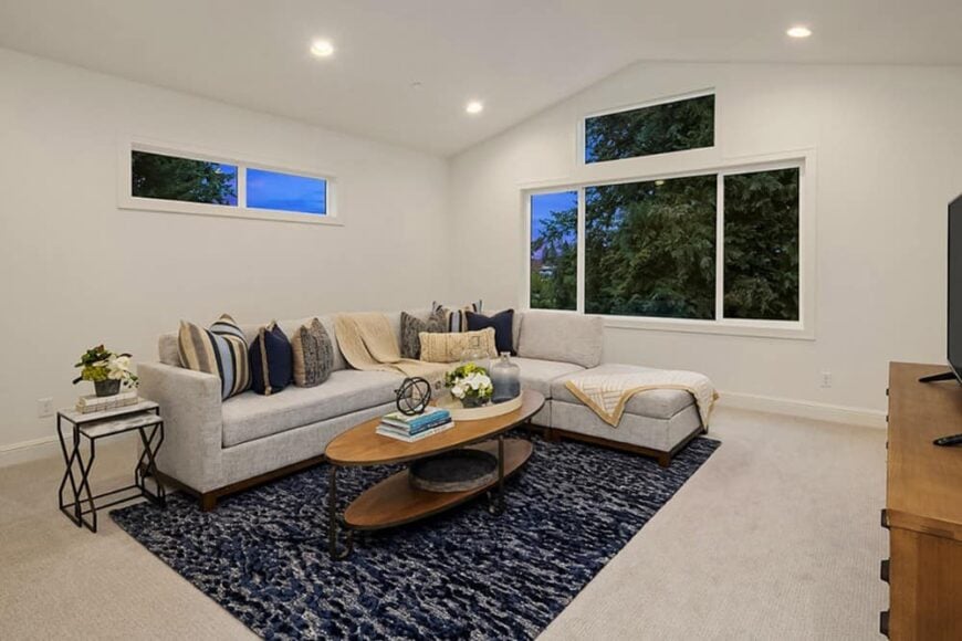 Bonus room with an L-shaped sofa, an oval coffee table, and a TV placed above the wooden cabinet.