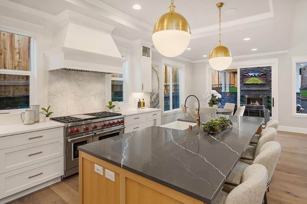 The kitchen offers white cabinetry, marble countertops, and a breakfast island fitted with a farmhouse sink.