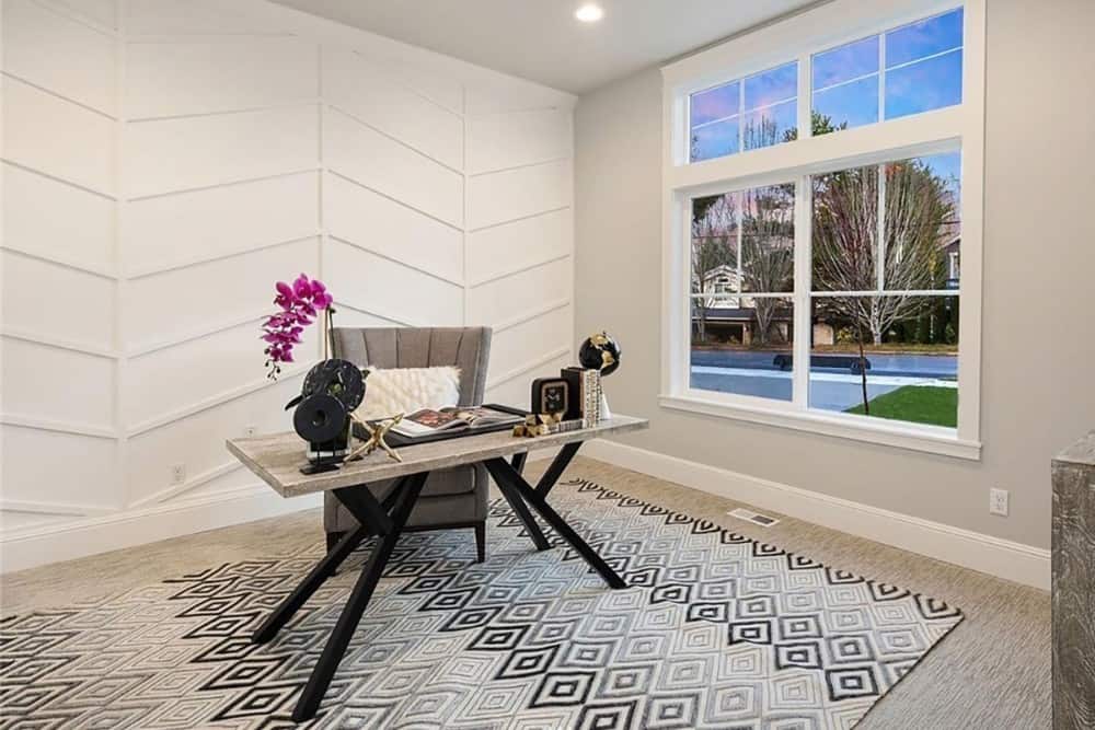 Home office with a chevron paneled accent wall, a wooden desk, and a gray upholstered chair over a patterned area rug.