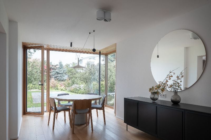 Cherry tree house living space with big circle mirror above cabinets.