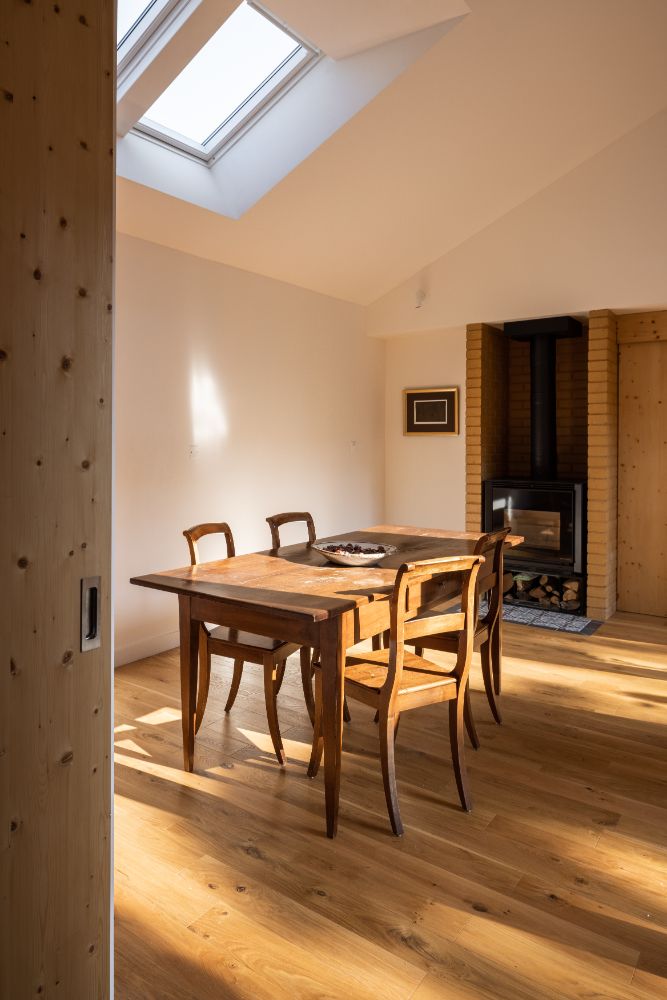 Dining area with four seater wooden dining table and wooden stove under the shed type ceiling.