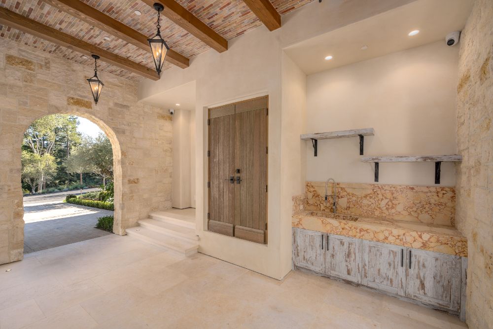 An open house with cathedral-beamed ceiling, hanging pendant lighting and marble sink.