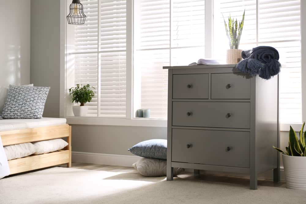 Bedroom with a gray dresser topped with blanket and potted plant.