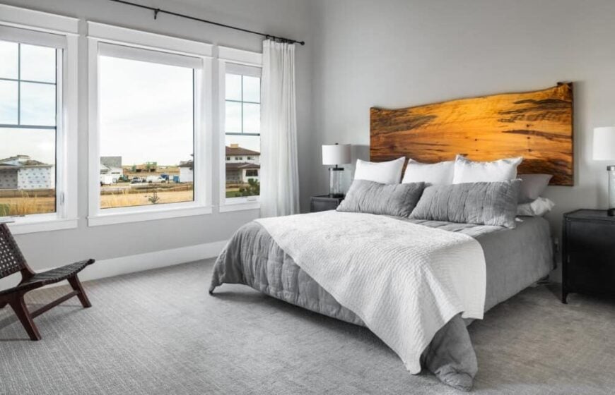 Primary bedroom with carpeted floor and a comfy bed with a custom wooden headboard.