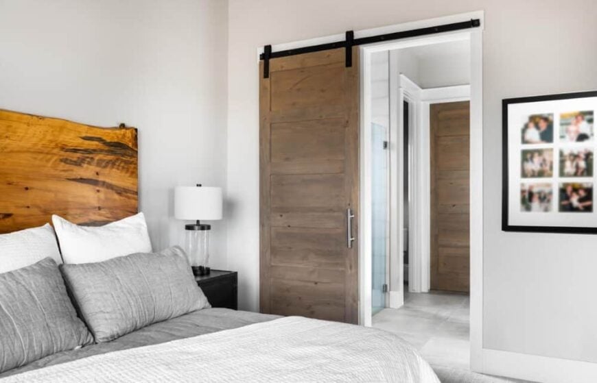 A sliding barn door across the bed reveals the primary bathroom and walk-in closet.