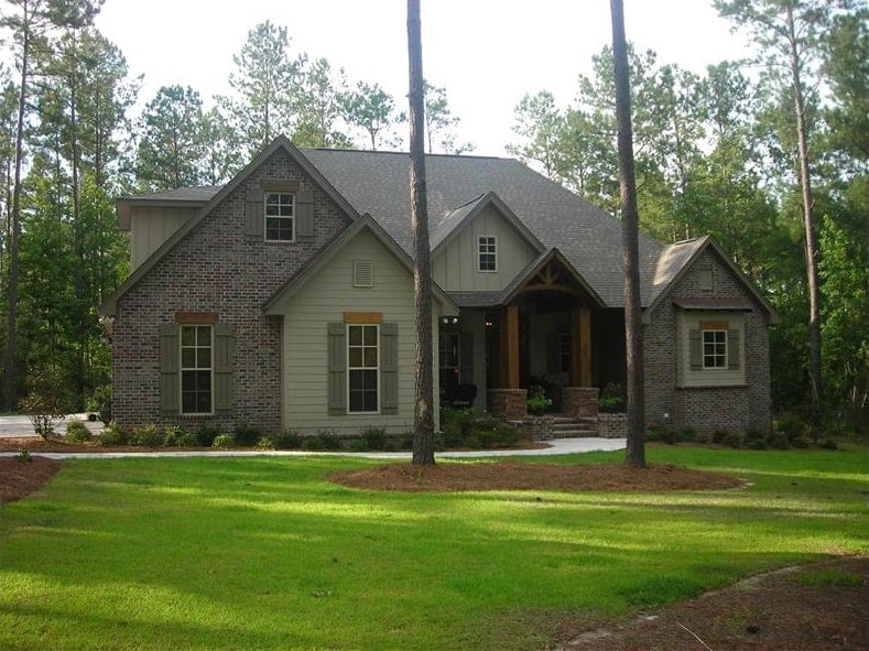 Front exterior view showcasing its multiple gables, stone and siding, shuttered windows, and a covered entry.
