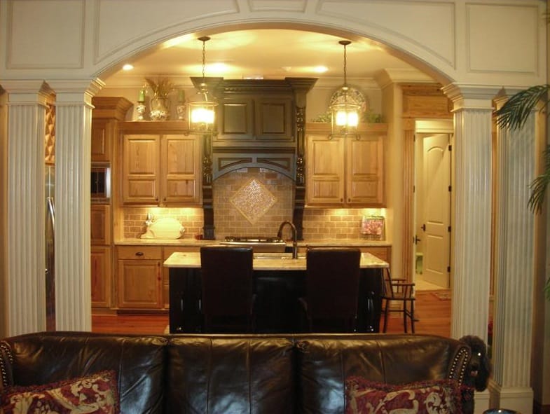 View of the kitchen from the great room bordered with an archway and double columns.