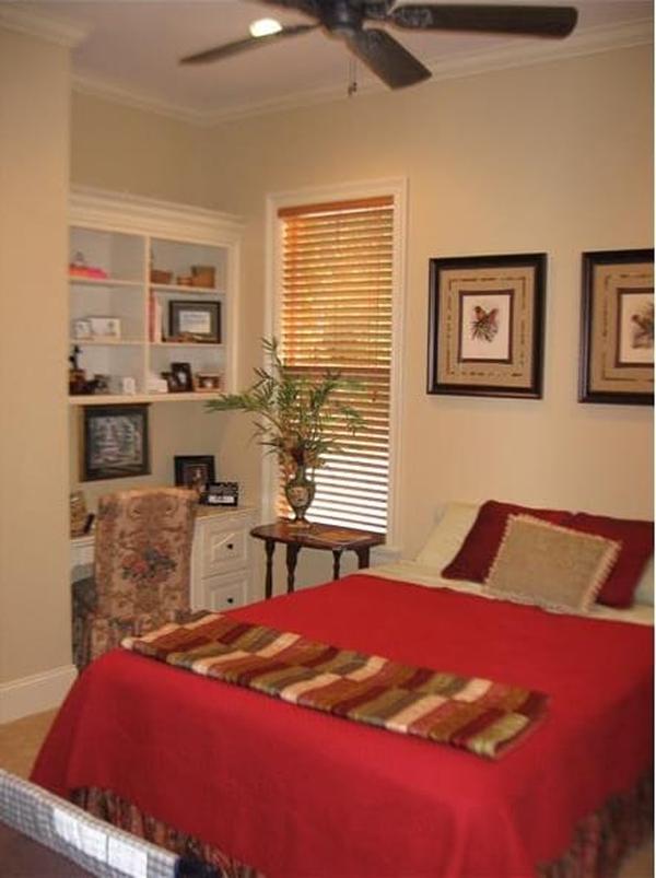 The primary bedroom has carpet flooring and a wrought iron bed complemented with a wooden table at its end.