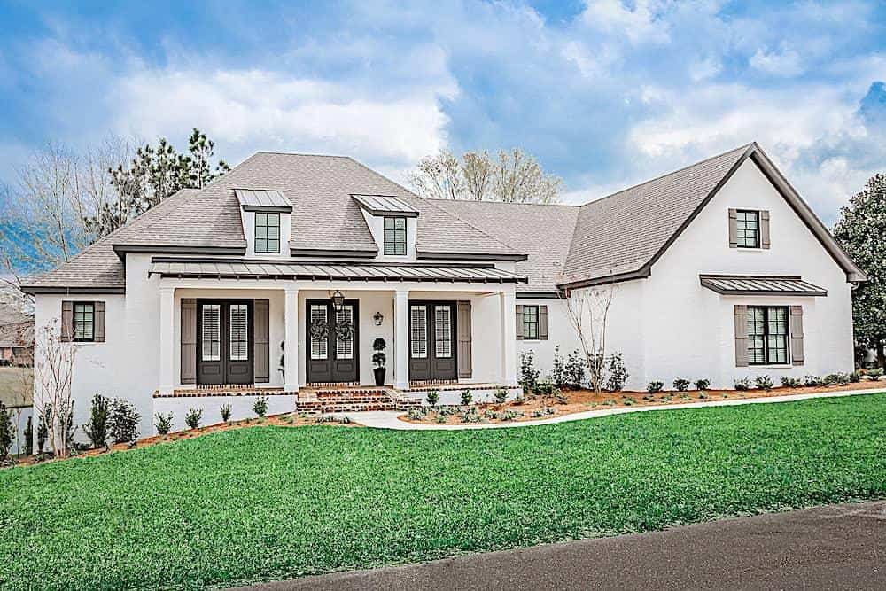 Front exterior view showcasing its white stucco siding and a covered entry porch topped with twin shed dormers.